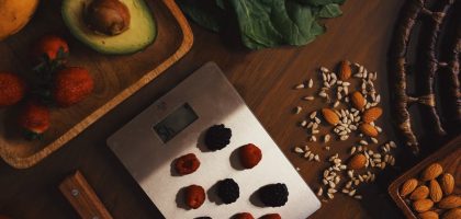 Top view of composed raw almond with seeds and avocado on table with berries on scales for cooking healthy dish