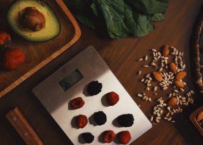 Top view of composed raw almond with seeds and avocado on table with berries on scales for cooking healthy dish