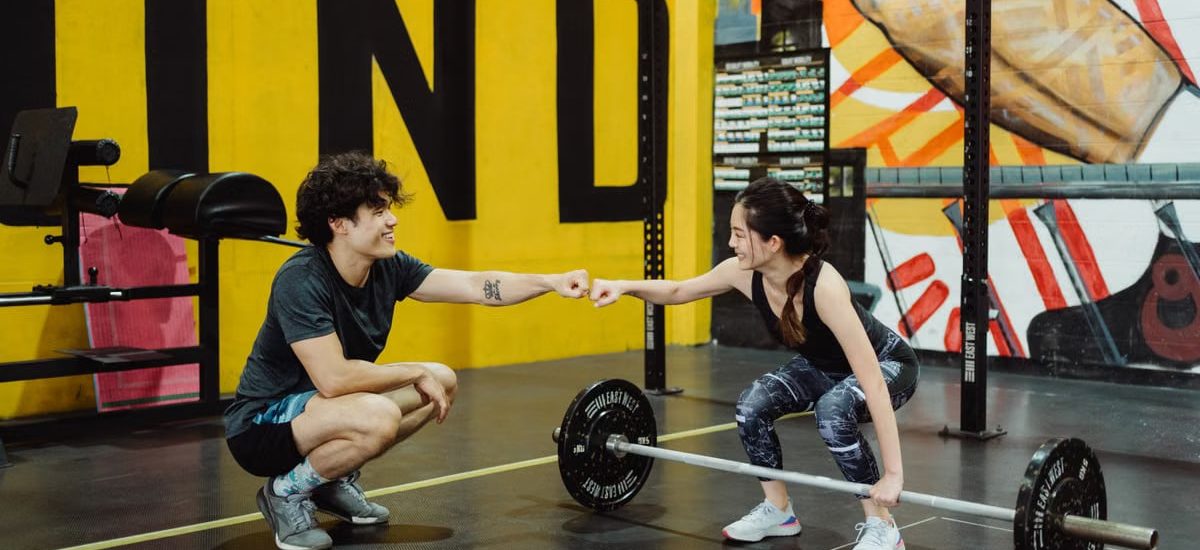 Man and woman in gym sharing a fist bump to celebrate a workout session.