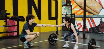 Man and woman in gym sharing a fist bump to celebrate a workout session.